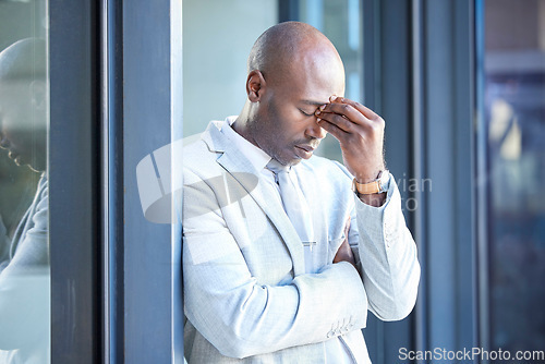 Image of Stress, headache and tired African businessman outside the office taking a break from work. Frustrated, burnout and overworked professional manager working overtime at his workplace in the urban city