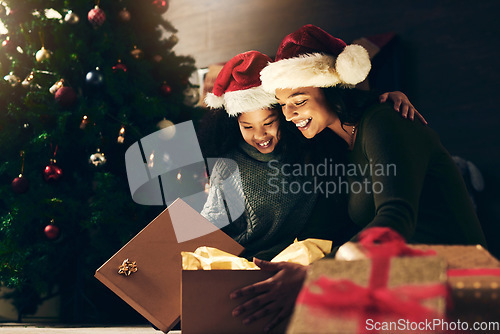 Image of Night, mother and child with a gift for Christmas in celebration of a happy family holiday in winter at home. Love, giving and exited mom opening a present box with girl kid to celebrate festive time