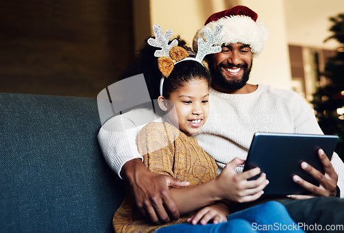 Image of Family Christmas, tablet and girl with father on sofa in living room streaming video, movie or web browsing. Love, xmas and kid with dad on digital touchscreen bonding, caring and enjoying holiday.