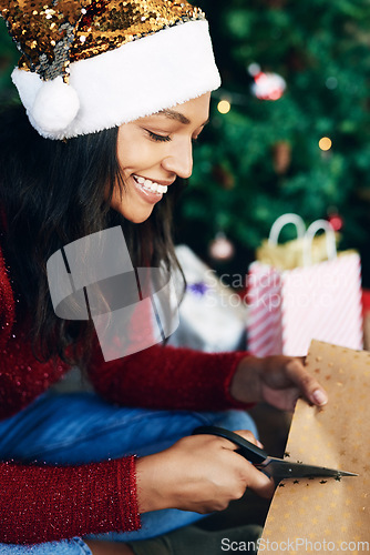 Image of Christmas, woman and scissors for cutting paper to wrap gift in home. Xmas spirit, holiday and happy female from India with clippers to cut wrapping paper for packing gifts or presents in house alone