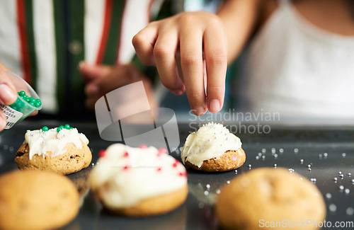 Image of Girl hands, decorating cookies and closeup with sparkles, cream or candy in kitchen for learning. Family home, child cooking and christmas biscuits on table for domestic skills, education or teaching