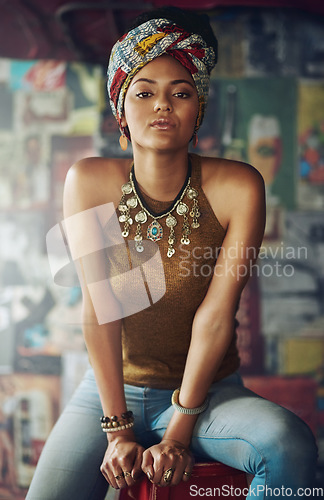 Image of Portrait, fashion and heritage with a black woman on a stool indoors with an African style turban. Model, culture and tradition with an attractive young female feeling empowerment or proud