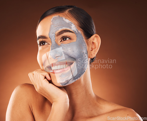 Image of Face, beauty skincare and woman with clay mask in studio isolated on a brown background. Makeup, aesthetics and happy female from Canada thinking about healthy and glowing skin after facial treatment