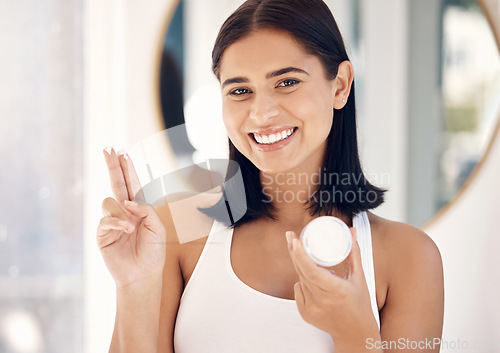 Image of Face, beauty and skincare with a woman in the bathroom of her home to promote a cosmetic product. Portrait, antiaging and treatment with an attractive young female applying lotion to her skin