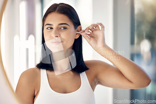 Image of Beauty, hygiene and ear cleaning with a woman using an earbud in the bathroom mirror of her home. Health, wellness and grooming with a female using a cotton bud to clean her eyes in the house