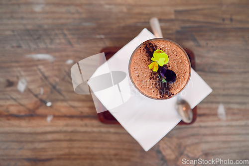 Image of Coffee shop, barista and hot chocolate art flowers decoration for relaxing and sweet drink break. Cafe, artisan and mocha foam with cocoa powder sprinkle in glass on wood table top view.