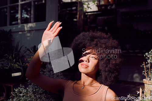 Image of Sun, shadow and hand with a black woman covering her face from the light while standing outdoor. Beauty, afro and sunlight with an attractive young female blocking her head and skin from sunshine