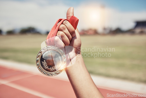 Image of Closeup, hand and medal for winning, success on track for marathon for wellness, outdoor and sports. Victory, athlete and winner holding gold award, achievement and competition for goal and champion.