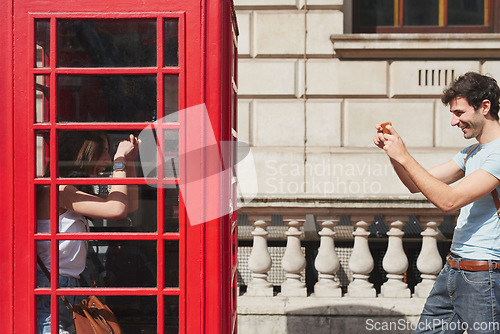 Image of Couple, phone booth and picture in London, england and travel holiday, summer and fun adventure together in the city. Young man, woman and international vacation, urban town and photo with smartphone