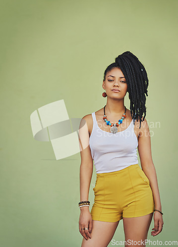 Image of Portrait of black woman, urban fashion and model posing on green wall of studio background for trendy African style, jewelry and women clothing. Cool model attitude, dreadlocks girl and natural hair