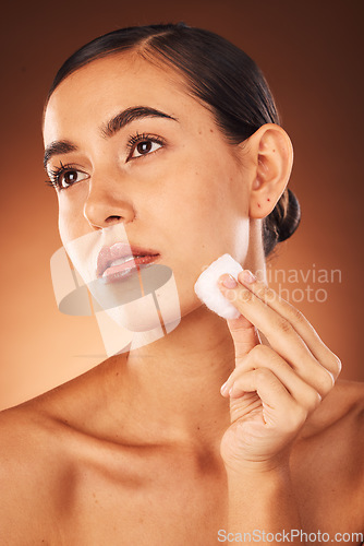 Image of Woman, skincare beauty and cotton for face, health and cleaning for cosmetic glow by brown studio backdrop. Model, cottonwool and skin with moisturiser, wellness and natural cosmetics by backdrop