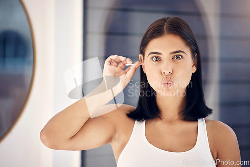 Image of Woman, mirror and cleaning ear in morning in home, bathroom and self care for personal hygiene. Girl, health and beauty in house for clean, self love and cleanliness with q-tip for wax in Los Angeles