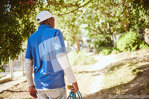 Image of Outdoor animal shelter, cleaning and worker with hose walking in nature to clean for volunteer work. Community, charity and black man working at rescue center for dogs, animals and adoption of pets