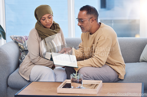 Image of Muslim couple, bonding and reading book, holy koran or traditional prayer quran on sofa in house or home living room. Islamic man, middle aged woman and mature people in muslim pray for eid mubarak