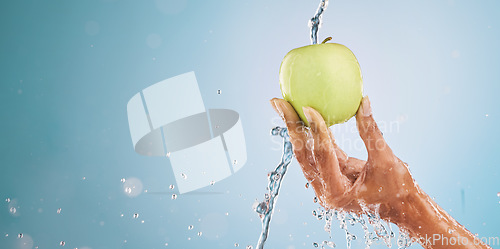 Image of Water splash, hand of woman and apple in studio on a blue background mockup. Fresh food, cleaning hygiene and female model washing fruit for healthy diet, vitamin c or nutrition, skincare or beauty.