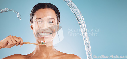 Image of Black woman, toothbrush and brushing teeth with a water splash and toothpaste on blue studio background for dental health and wellness. Portrait and face of model cleaning mouth with eco brush