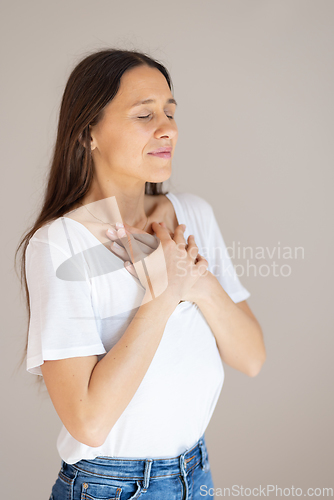 Image of Woman with hands on chest doing breathing exercise at home