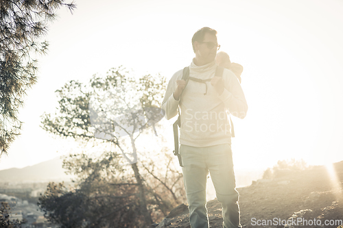 Image of Young father carrying his infant baby boy son in backpack while tracking around Malaga, Spain in sunset. Family travel and vacation concept