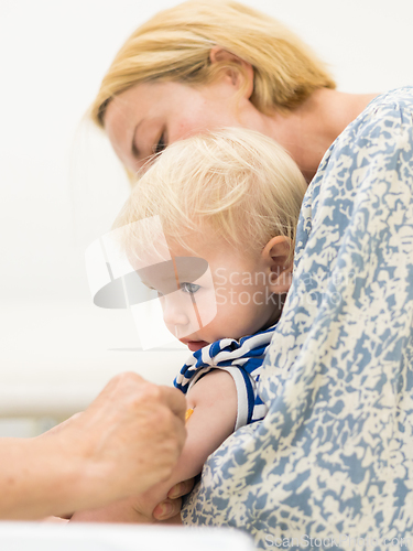 Image of Child beeing vaccinated by pediatrician in presence of his mother. Preventive vaccination against Diphtheria, whooping cough, tetanus, hepatitis, haemophilus influenzae, pneumococcus, poliomyelitis