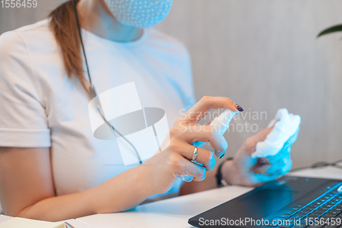 Image of Woman disinfects the surface of the phone