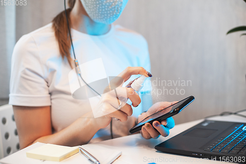 Image of Woman disinfects the surface of the phone