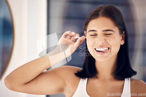 Image of Cotton bud, woman and cleaning ear in bathroom for self care. Personal hygiene, wellness and face of happy, young and comic female from India with tongue out and tool to remove earwax in house alone.