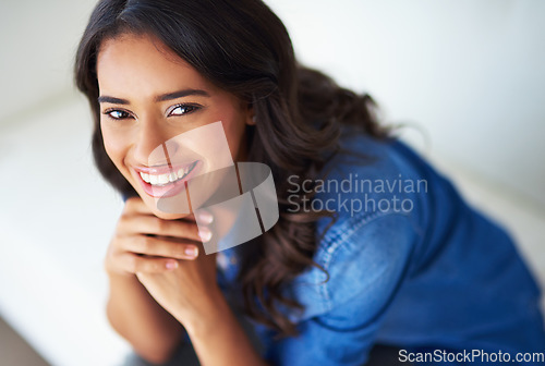 Image of Portrait, face and happy with a black woman in her home to relax alone on the weekend from above. Smile, freedom and sofa with an attractive young female resting in her house living room