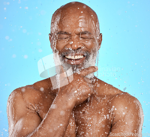 Image of Face, thinking and water splash of senior black man in studio isolated on a blue background. Skincare, hygiene and retired elderly male from Nigeria cleaning or washing for healthy skin and wellness.