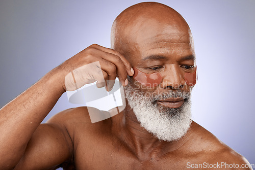 Image of Skincare, eye patches and senior man doing wellness, health and natural face routine in studio. Cosmetic, beauty and elderly African guy doing self care facial treatment isolated by purple background