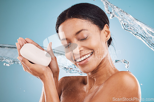 Image of Water splash, happy and black woman with soap for skincare, self love or self care in studio on blue background. Hands, shower and healthy African girl washing, grooming or cleaning her face or body