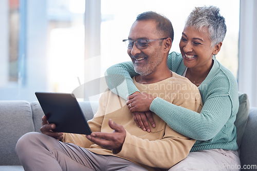Image of Old couple, tablet and relax with hug on sofa, social media or streaming movie. Love, retirement and elderly man and woman hugging or embrace on couch in living room while internet browsing on tech.