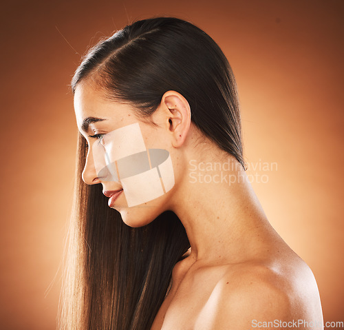 Image of Face, beauty and hair with a model woman in studio on a brown background to promote keratin treatment. Haircare, hairstyle and wellness with an attractive young female posing for natural hair care