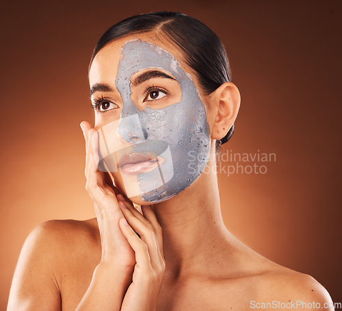 Image of Woman, face skincare and mud mask on orange background in studio self care, dermatology or acne treatment. Beauty model, facial mud and cream product for collagen maintenance, cleaning detox or scrub