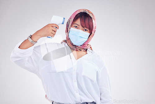 Image of Muslim woman, covid face mask and thermometer gun on white studio background for marketing, virus and healthcare mockup. Portrait of islam model in hijab with medical thermal scanner for safety