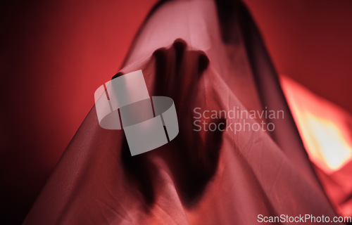 Image of Hand, fabric and red with a person under a sheet in a bedroom or studio on a red background for psychology. Hands, silhouette and shadow with an adult struggling with mental health, anxiety or fear