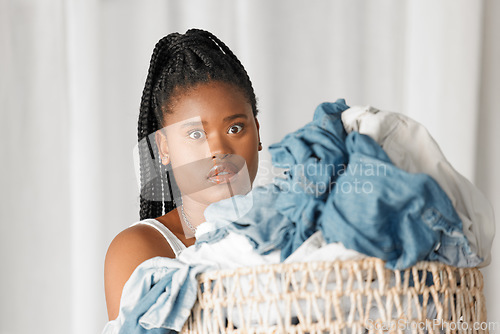 Image of Portrait, laundry and wow with a black woman cleaner carrying a basket of clothing for washing in her home. Cleaning, face and shock with a female housekeeper doing housework or chores with surprise