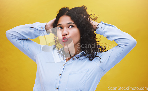 Image of Freedom, beauty and youth, a black woman blowing a kiss or pouting with yellow background. Portrait of happy girl with hands in curly hair, kissing air. Fun, crazy and excited expression on female.