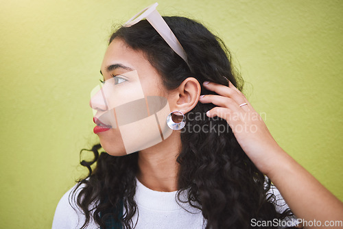 Image of Beautiful, young stylish and carefree African American black millennial woman. Long curly hair, with sunglasses on her head, standing against a lime background, looking pretty and bold