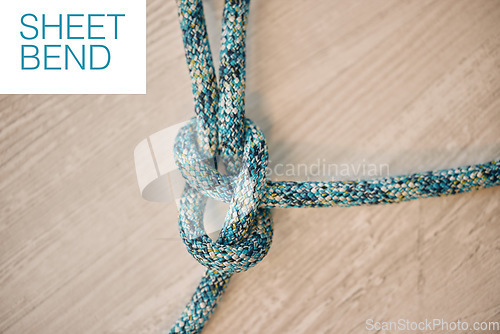 Image of Hiking rope in a knot against a wooden floor background in a studio from above. Strong sheet bend tie, cable or cord equipment to secure safety while mountain climbing or extreme sports for athletes.