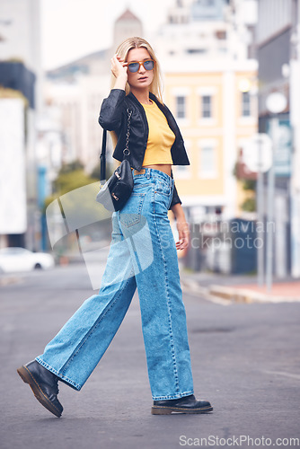 Image of Portrait of fashion, beauty and cool woman with stylish sunglasses walking in a street in the city. Trendy blonde female looking carefree, hipster and confident while exploring urban town outdoor