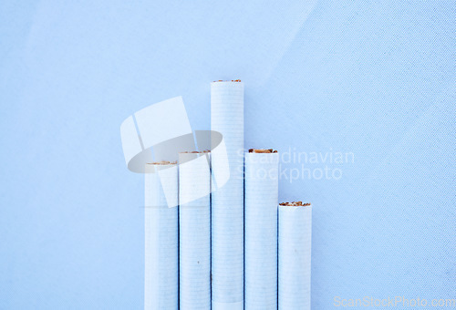 Image of Cigarettes, table and mockup for healthcare habit, drug danger and lung cancer disease awareness on blue background. Zoom, tobacco smoke product and pack of smoking wellness safety on mock up texture