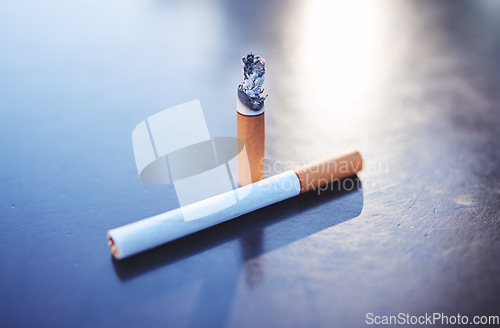 Image of Smoking, tobacco and burning cigarette on table, close up of two cigarettes. Awareness for substance abuse, nicotine and unhealthy lifestyle addiction as cause for health issue, risk and lung cancer