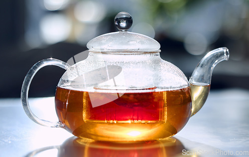 Image of Tea, drink and fresh with a bag in a glass pot for drinking, refreshment or brewing on a table in the kitchen. Herbal, health and natural with an organic beverage to boost your immune system