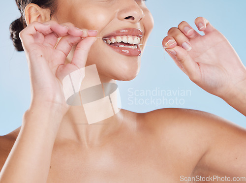 Image of Woman flossing her teeth with dental floss for oral care, healthcare and hygiene in a studio. Girl with wellness, healthy and clean lifestyle doing her mouth routine for tooth and gum health.