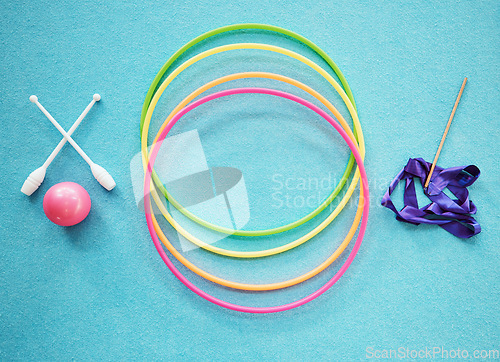Image of Gymnastics, dance and fitness with a hula hoop, ribbon and bars on an empty blue floor from above for exercise or training. Exercise, workout and still life with equipment for dancing or performance