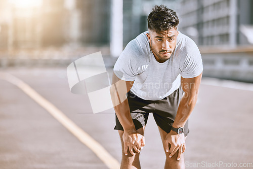 Image of Man resting, after jogging and running in the city for fitness. Healthy, fit and alone runner catching his breath after a run in the morning. Training, cardio and relaxing after a workout in town.