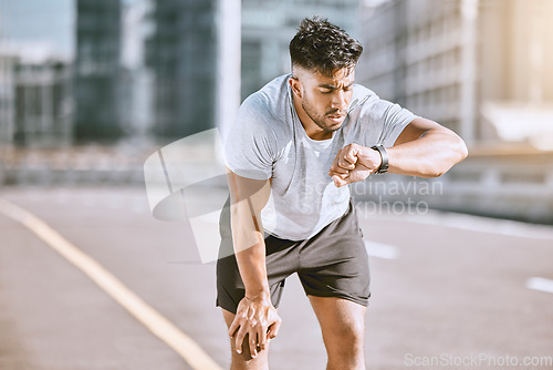 Image of Fitness, tired and runner checking watch for running speed, pace and time in routine workout, exercise and city training. Fit, active and healthy man monitoring wellness, endurance and cardio health