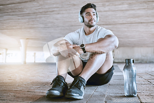 Image of Athlete with headphones and water bottle on a relax break listening to music after his training exercise in the city with lens flare. Young sports man with audio fitness technology and workout gear