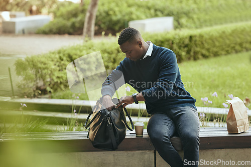 Image of Businessman city park, food and lunch break with coffee or tea drink in paperbag. Young African entrepreneur looking in bag for strategy notebook and sitting outside in urban environment alone