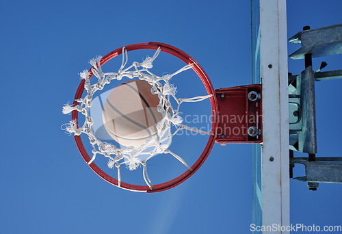 Image of Basketball sports winner throwing, shooting hoops and slam dunk for points, score and performance during sports, competition and game match from below outdoor. Background of net, hoop and goal target